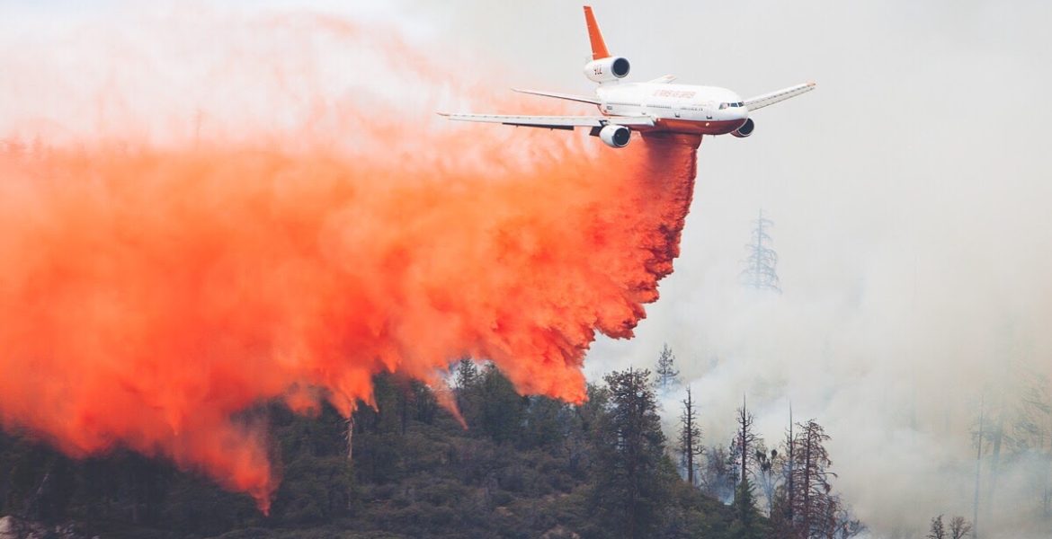 Small plane dropping fire retardant onto a wildfire.