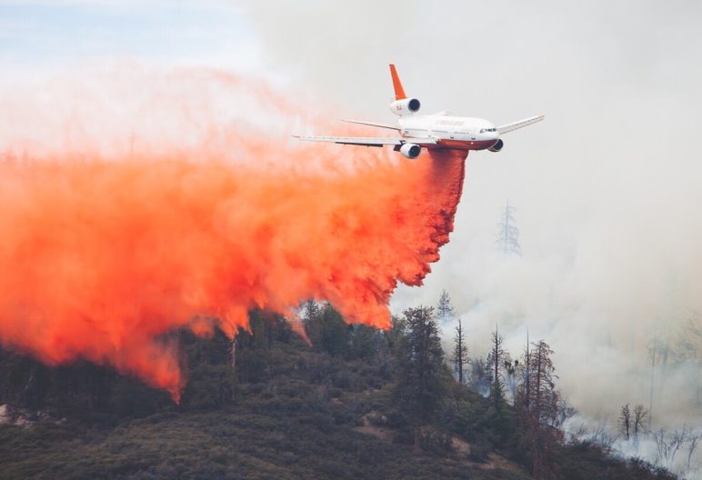 Small plane dropping fire retardant onto a wildfire.