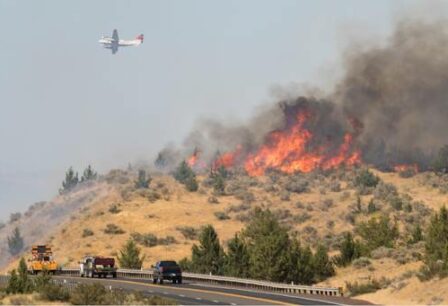 Firefighting airplane flying above a wildfire.