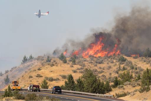 Firefighting airplane flying above a wildfire.