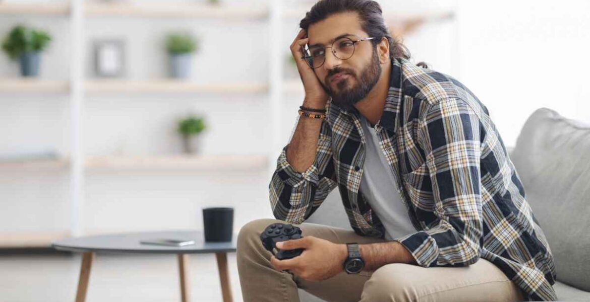 Bored person sitting on a couch holding a video game controller.