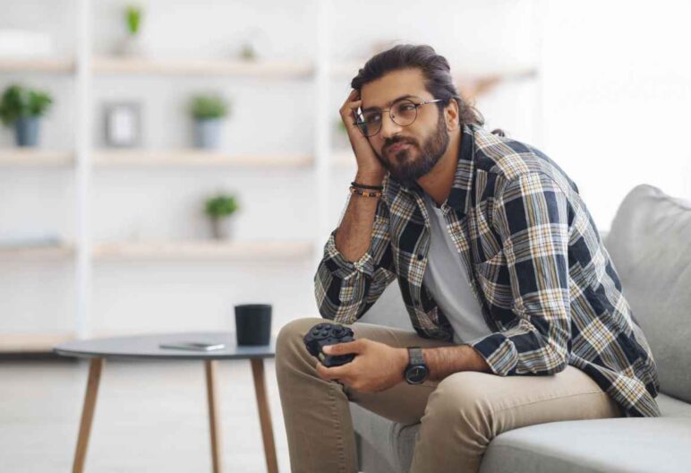 Bored person sitting on a couch holding a video game controller.